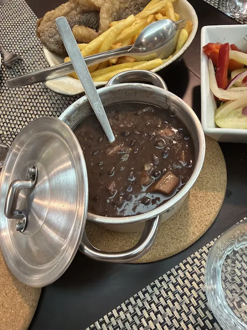 Feijoada servida na panela, com salada e batata frita